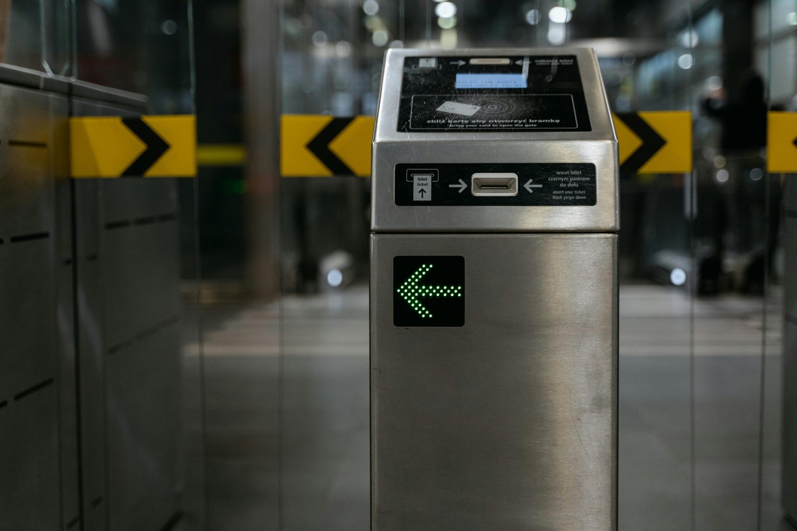 A modern ticket gate with an illuminated arrow for access control in transit systems.